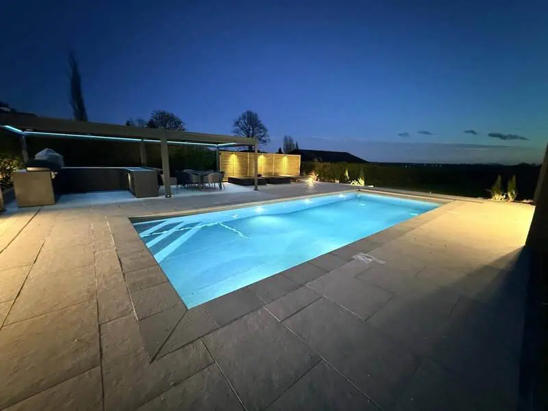 Contemporary pool garden with luxury paving and evening lighting