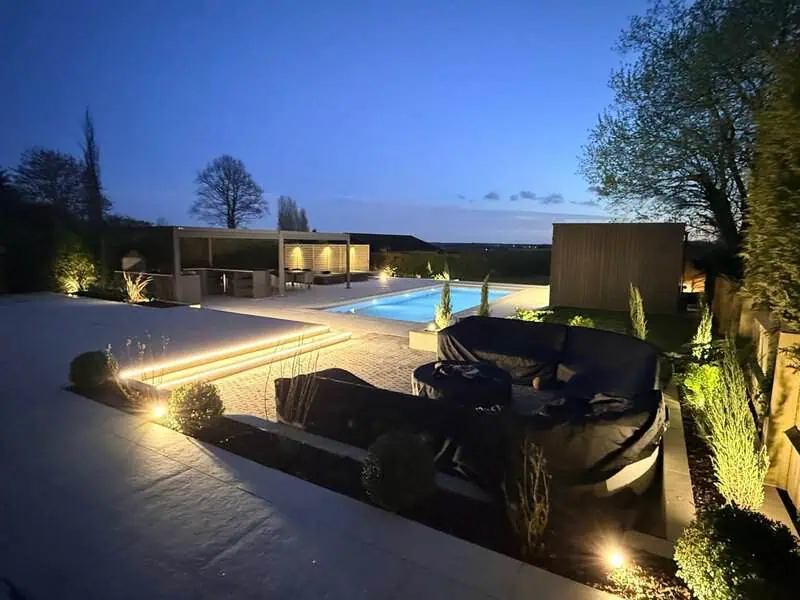Luxury garden seating area with pool, pergola and evening lighting